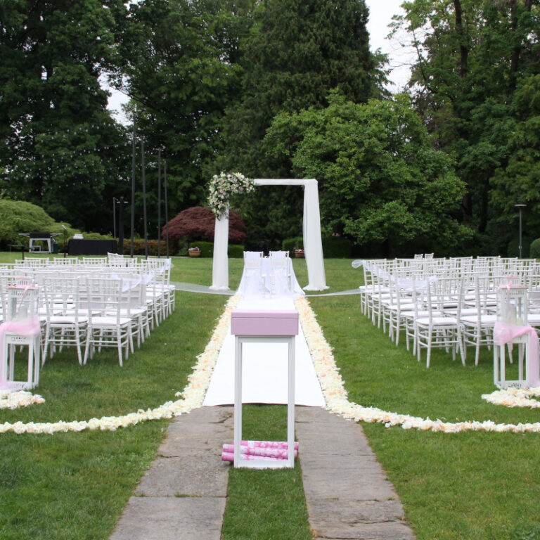 Vista delle zona cerimonia di matrimonio con sedie ospiti e sedie degli sposi incorniciate da arco in alluminio decorato